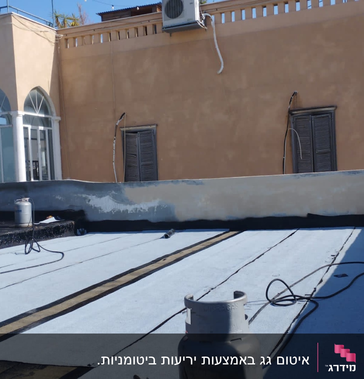 גג עם יריעות איטום, בלוני גז וצינורות.